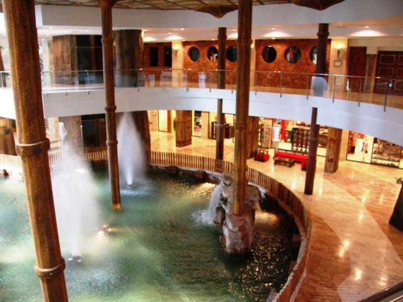 Innenhof mit Rundgang, Holzsäulen, Wasserbecken und sprudelnden Fontänen.