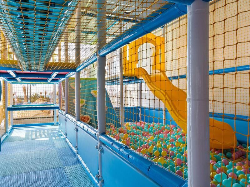 Bunter Indoor-Spielplatz mit Bällen, Rutschbahn und Sicherheitsnetz in blau-gelber Farbkombination.