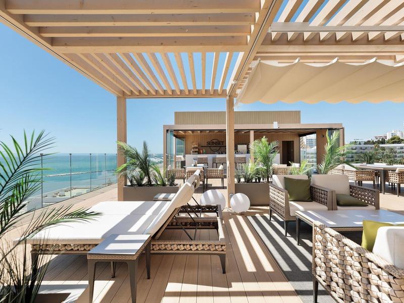 Moderner Außenbereich mit Holzpergola, Loungemöbeln, Pflanzen und Meerblick.