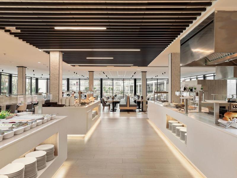 Moderne Kantine mit großen Fenstern, langen weißen Buffets und Holzdeckenakzenten.