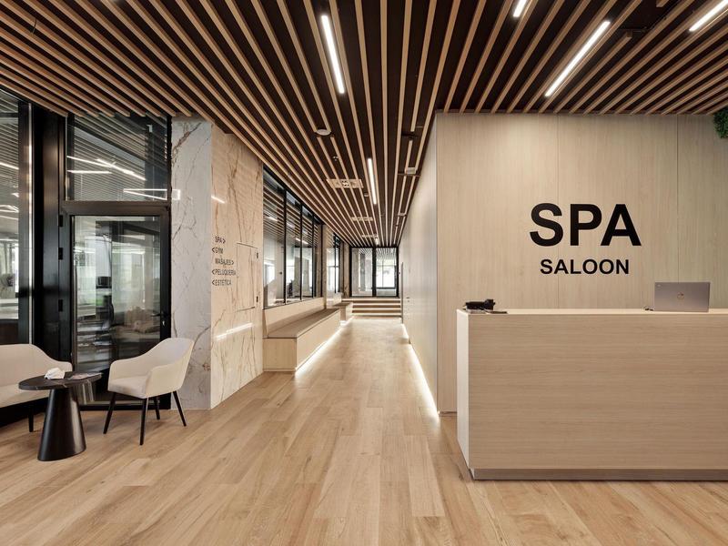 Moderner Spa-Empfang mit Holzfußboden, Altholzdeckenleisten, Sitzbereich und hellen Holzmöbeln.