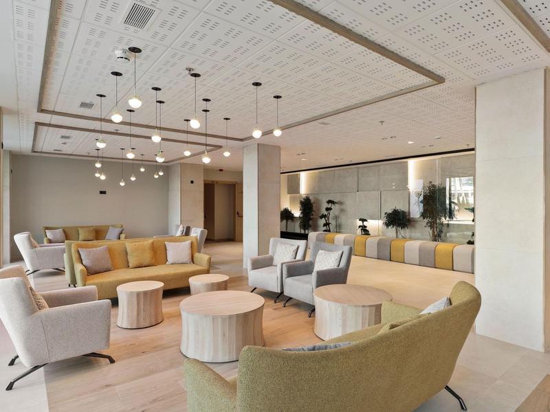 Modern eingerichteter Wohnbereich mit runden Tischen, verschiedenfarbigen Sofas und Deckenbeleuchtung.