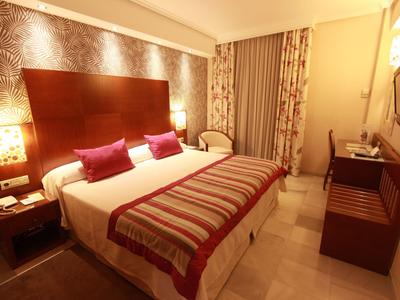 Ein gemütliches Hotelzimmer mit großem Bett, dekorativen Kissen und warmem Licht.