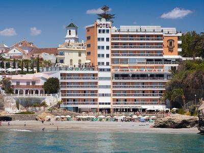 Ein mehrstöckiges Hotel mit Balkonreihen direkt am sandigen Strand und klarem blauem Wasser.