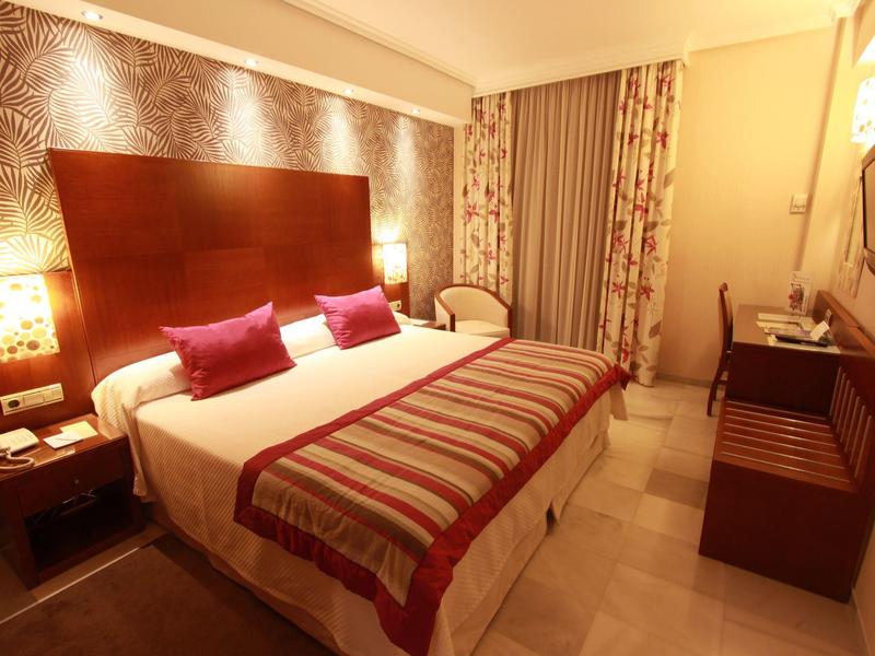 Ein gemütliches Hotelzimmer mit großem Bett, dekorativen Kissen und warmem Licht.