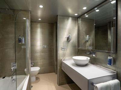 Modernes Badezimmer mit Glas-Duschkabine, Waschbecken auf der Arbeitsplatte und großem Spiegel.