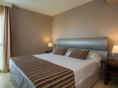 Gemütliches Hotelzimmer mit Doppelbett, zwei Nachttischen und warmem Licht.