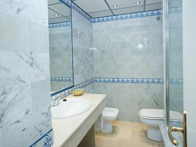 Helles Badezimmer mit Marmorfliesen, großem Spiegel, Waschbecken, Toilette und Bidet.