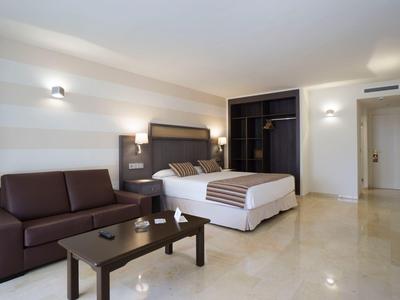 Modernes Hotelzimmer mit großem Bett, Sofa, Tisch und geräumigem Kleiderschrank.