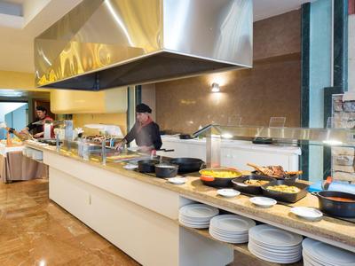 Buffetbereich mit Koch, der Speisen zubereitet, und verschiedenen Gerichten auf der Theke.