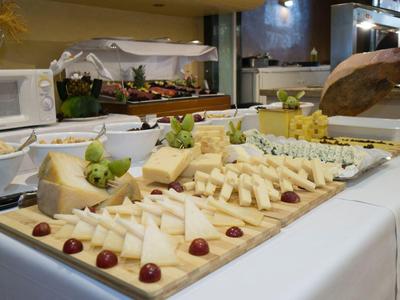 Buffet mit verschiedenen Käsesorten, Trauben und Feigen auf einem weißen Tisch.