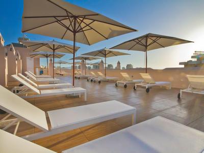 Dachterrasse mit Liegestühlen und Sonnenschirmen bei Sonnenuntergang