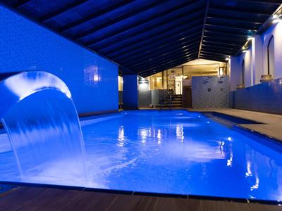 Beleuchteter Hotelpool mit Wasserfallfunktion und modernem Design in der Nacht.
