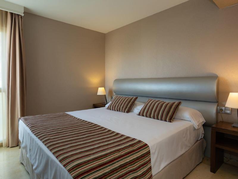 Gemütliches Hotelzimmer mit Doppelbett, zwei Nachttischen und warmem Licht.