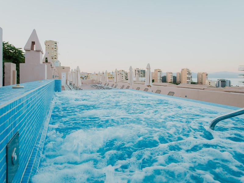 Whirlpool auf einer Dachterrasse mit Blick auf Stadtgebäude unter klarem Himmel