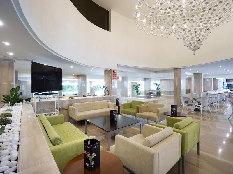 Moderner Hotellobbybereich mit Sitzgruppen, Pflanzen und einem großen Kronleuchter.