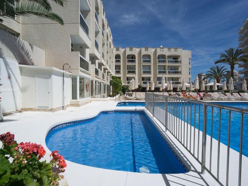Moderner Hotelpool mit klarem blauem Wasser und umliegenden Liegestühlen und Palmen.