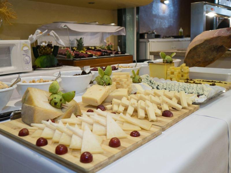 Buffet mit verschiedenen Käsesorten, Trauben und Feigen auf einem weißen Tisch.