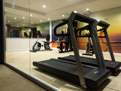 Nowoczesny sprzęt fitness w jasnym, dobrze oświetlonym pokoju treningowym z lustrzaną ścianą.