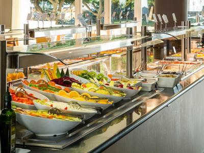 Buffet mit frischem Gemüse, Salaten und warmen Speisen in weißen Schalen und Metallbehältern.