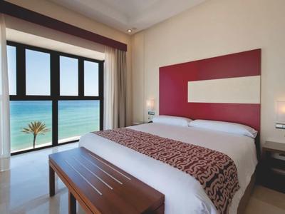 Großes weißes Hotelresort mit Pools, Tennisplatz und Garten in hügeliger, grüner Landschaft.