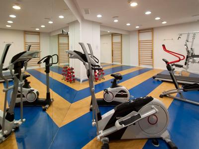 Salle de sport moderne avec équipements d'exercice et sol coloré dans un cadre hôtelier.