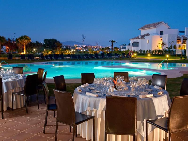 Abendliche Poolparty mit gedeckten Tischen und moderner Beleuchtung in warmem Ambiente.