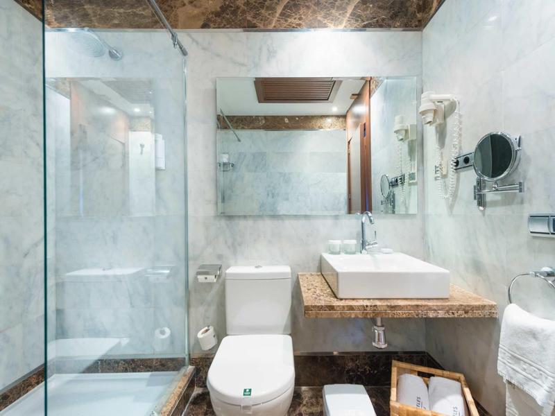 Helles modernes Badezimmer mit Glasdusche, weißer Toilette und rechteckigem Waschbecken auf Holztisch.