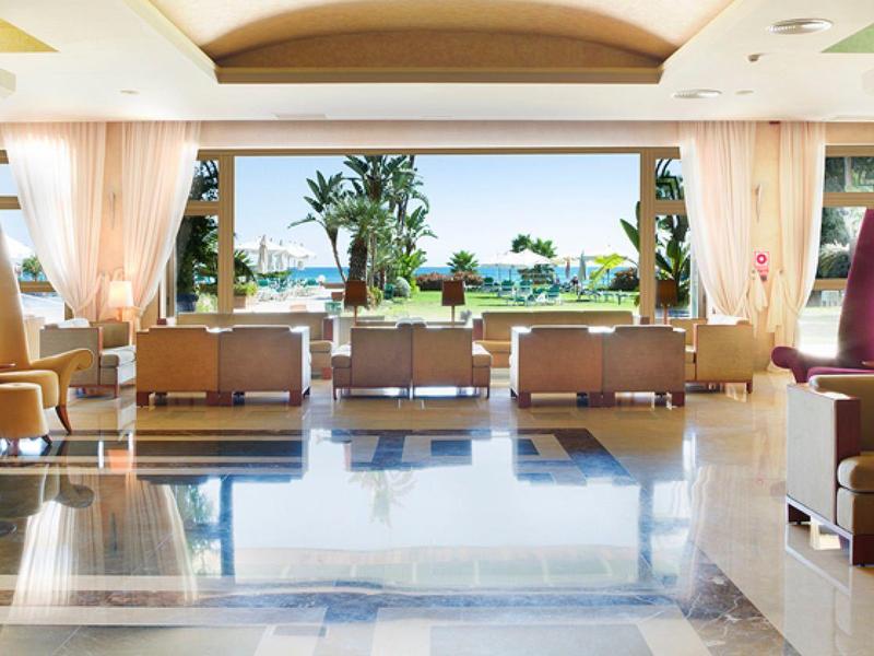 Heller, geräumiger Lobbybereich mit großen Fenstern, bequemen Sitzgruppen und Blick auf Meer.