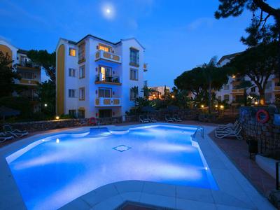 Oświetlony basen na zewnątrz przed wielopiętrowymi budynkami mieszkalnymi o zmierzchu.