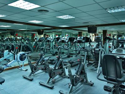 Großer Fitnessraum mit vielen Fahrradergometern und Spiegeln an den Wänden.