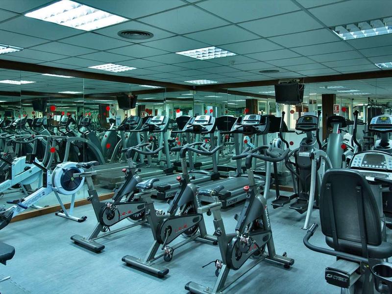 Großer Fitnessraum mit vielen Fahrradergometern und Spiegeln an den Wänden.