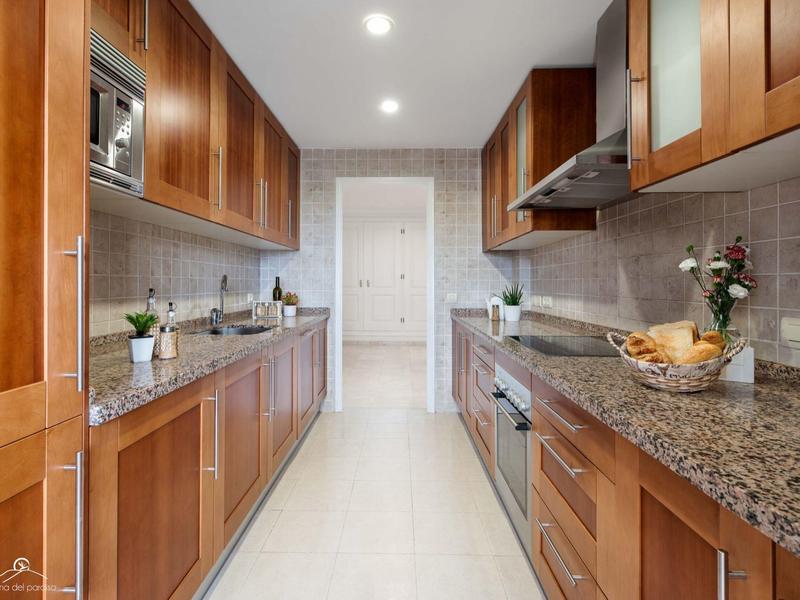 Moderne Küche mit Holzschränken, Granit-Arbeitsplatten und weißen Fliesenboden.