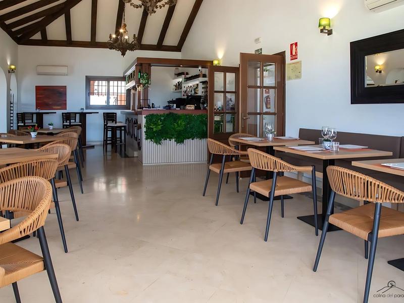 Heller Gastraum mit Holzmöbeln, weißem Boden und sichtbaren Deckenbalken.