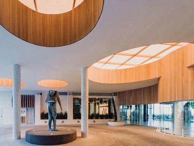 Modernes Hotellobby mit runden Holzdeckenöffnungen und einer Skulptur in der Mitte.