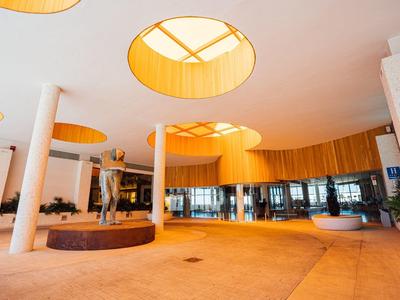 Moderner Hotel-Lobby-Bereich mit runden Deckenfenstern und einer Skulptur in der Mitte.