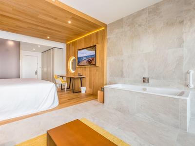 Modern eingerichtetes Hotelzimmer mit Badewanne und Holzakzenten