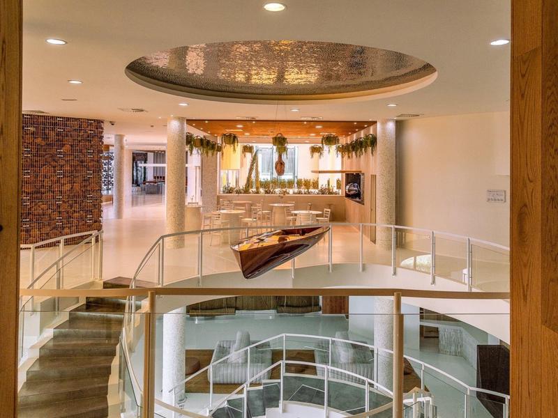 Modern gestalteter Innenraum mit runder Öffnung, Treppen, Holzelementen und weißen Geländern.