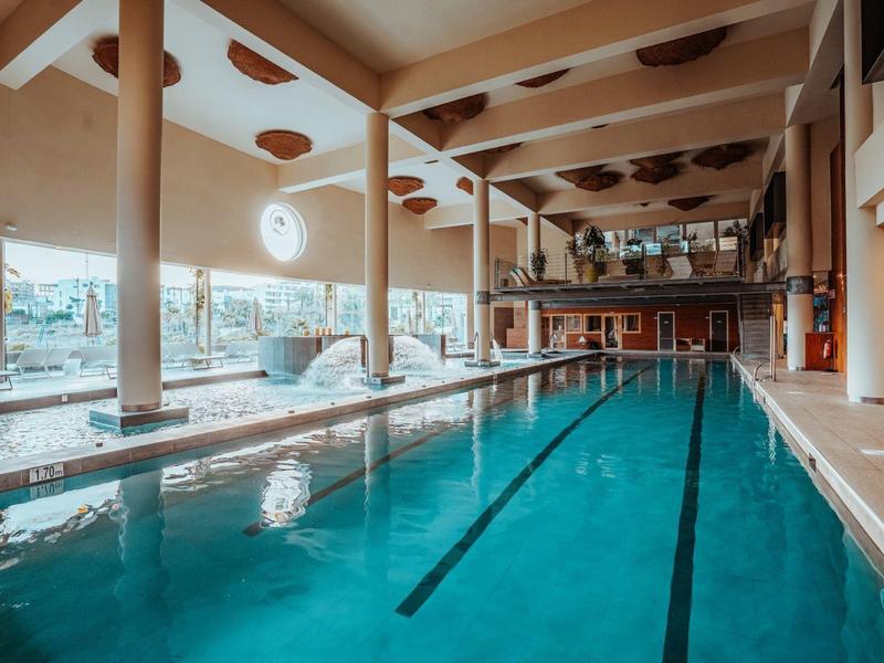 Innenpool in modernem Hotel mit großen Fenstern und Holzakzenten.