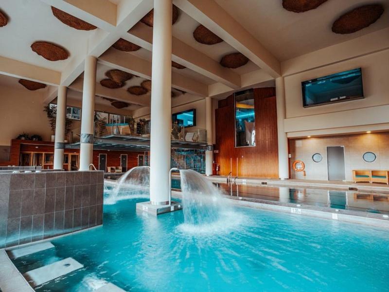 Innenpool mit Wasserspielen und Sitzbereich in einem luxuriösen Wellnesshotel.