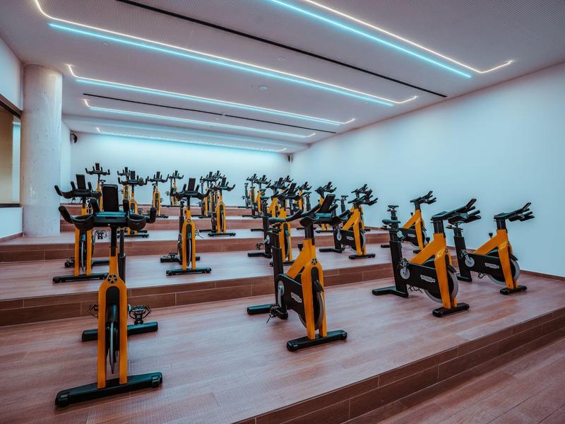 Innenansicht eines modernen Fitnessraums mit mehreren Indoor-Bikes und großen Spiegeln.