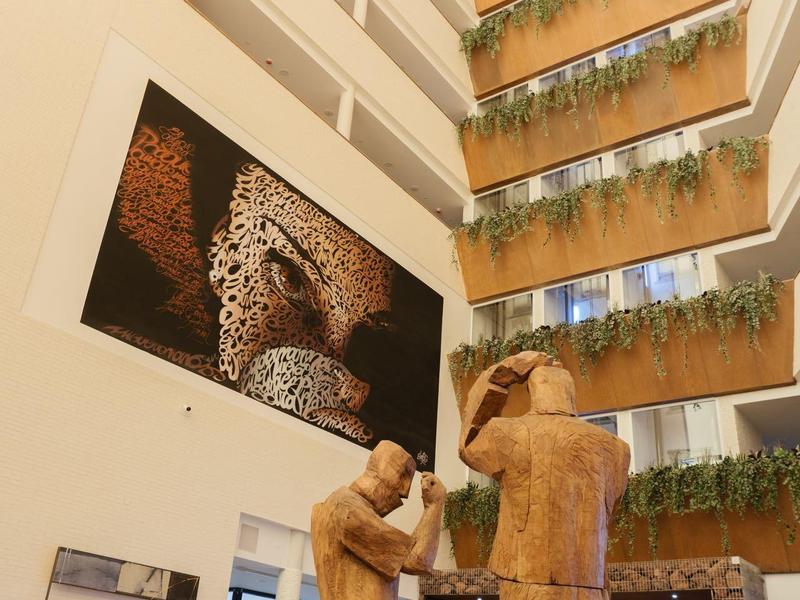 Heller Hotellobbyinnenraum mit großen Tierbildern und Brunnen im Mittelpunkt.