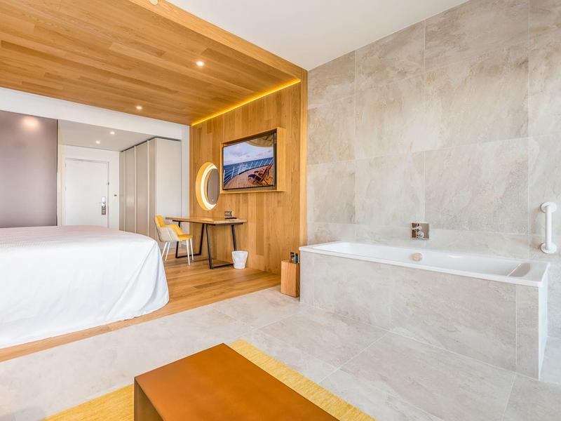 Modern eingerichtetes Hotelzimmer mit Badewanne und Holzakzenten