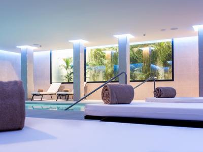 Moderner Wellnessbereich mit Pool, Liegen, großen Fenstern und sanfter Beleuchtung.