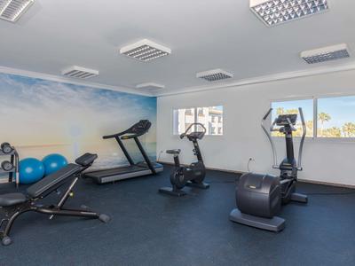 Palestra moderna con tapis roulant, cyclette, manubri e palle da ginnastica in una stanza luminosa.