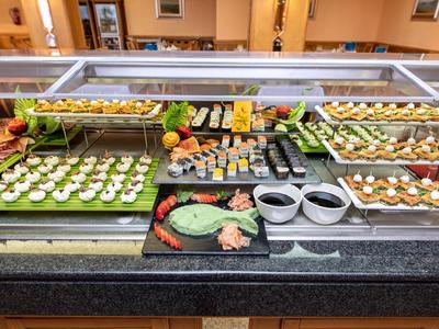 Buffet mit abwechslungsreichen Vorspeisen, Salaten und Saucen auf schwarzer Theke in Restaurant.