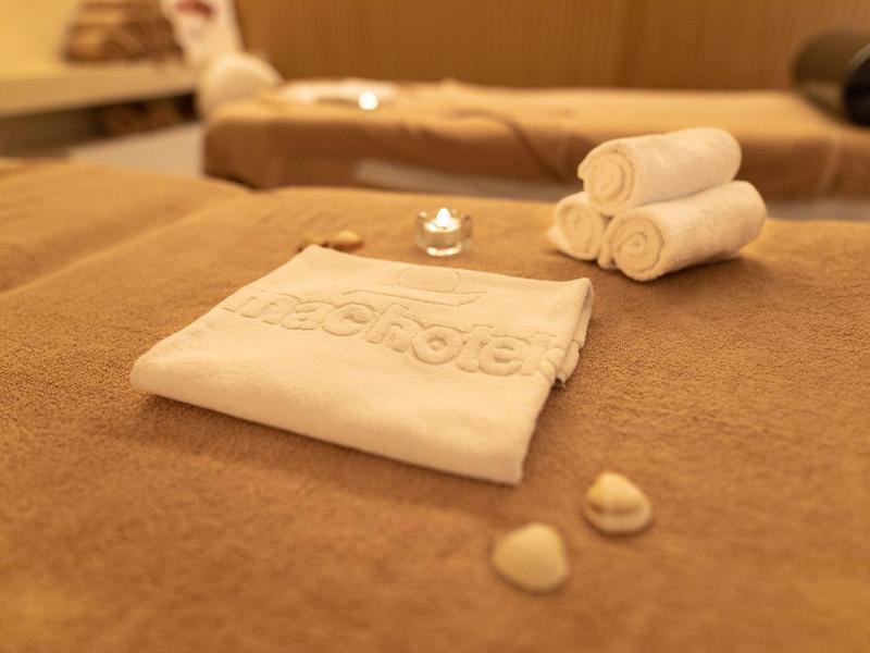 Weiche, braune Massagebank mit weißen Handtüchern und Wellnessaccessoires in warmem Licht.