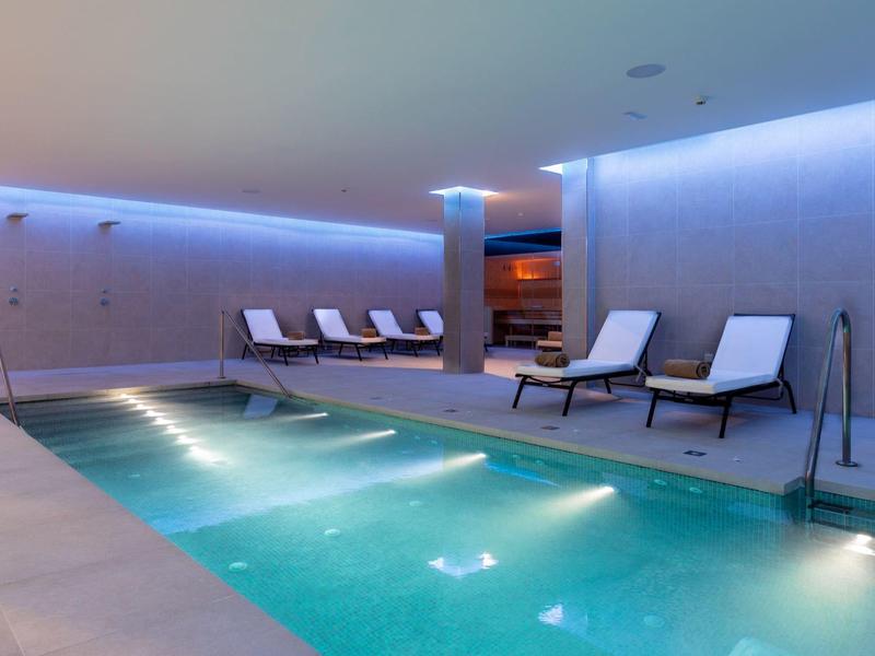 Hell beleuchteter Innenpool mit Liegestühlen und moderner, ruhiger Atmosphäre.