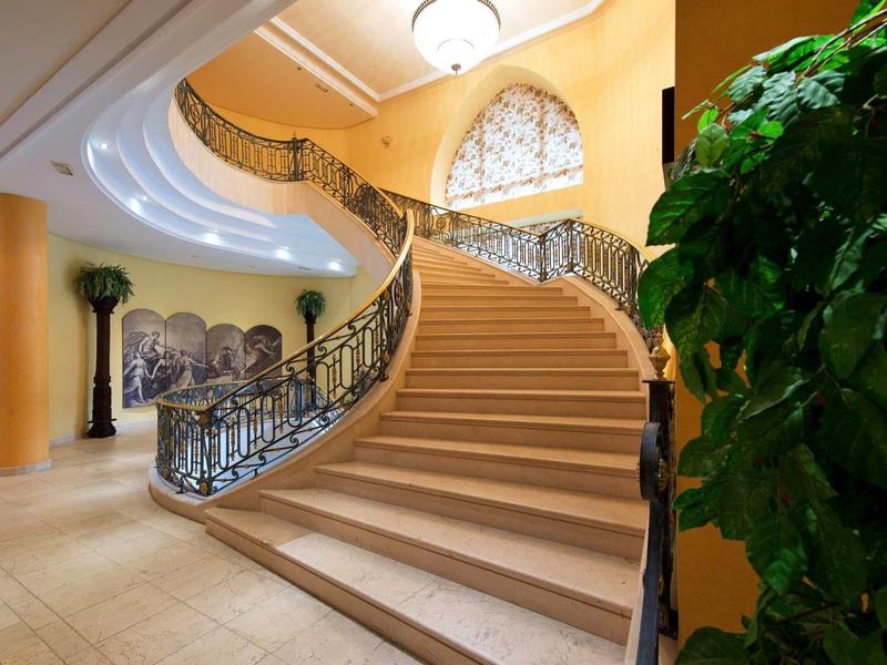 Elegante gewundene Treppe mit schmiedeeisernem Geländer und großem Fenster im hellen Eingangsbereich.