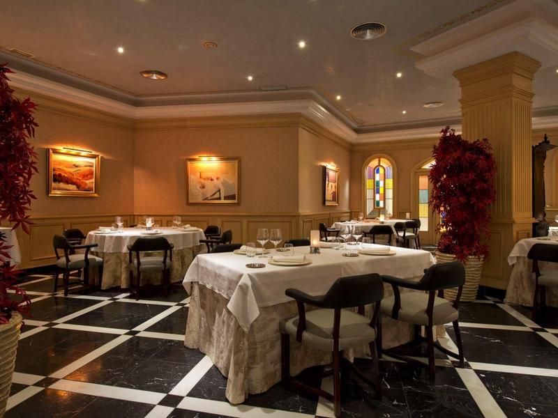 Elegantes Restaurant mit gedeckten Tischen, Holzstühlen und warmem indirektem Licht.